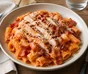 Rigatoni i krämig tomatsås med grillad kyckling, knaprigt bacon och riven parmesan