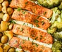 Laxfiléer och små potatisar med citron på en bakplåt
