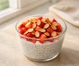Chia- och yoghurtpudding i ett glas med hackade jordgubbar och rostade mandelspån